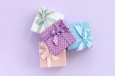 Küçük renkli hediye kutuları şeritler yığını mor bir arka plan üzerinde yatıyor. Üstten görünüm minimalizm düz yatıyordu.