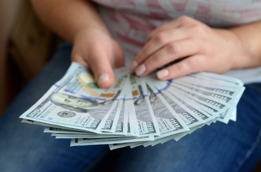 A yelpaze-in yüz dolar Bono tutan bir kız.