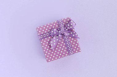 Küçük mor hediye kutusu kurdele ile mor bir arka plan üzerinde yatıyor. Üstten görünüm minimalizm düz yatıyordu.
