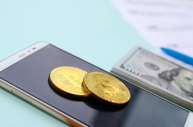 Vergi formları, yüz dolar faturaları ve açık mavi renkli smartphone ile Bitcoins yatıyor. Gelir vergisi beyannamesi.