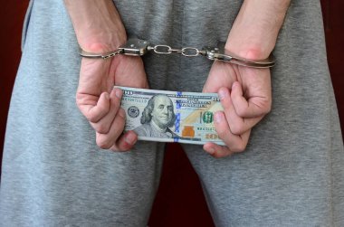 Kelepçeli elleriyle gri pantolon tutuklanan bir adam para büyük miktarda tutar. Arkadan görünüm.