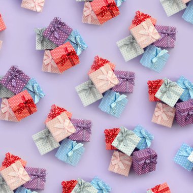 Küçük renkli hediye kutuları şeritler yığınları mor bir arka plan üzerinde yatıyor. Üstten görünüm desen minimalizm düz yatıyordu.