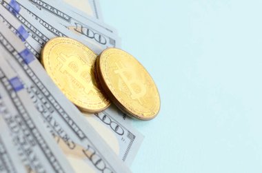 Altın bitcoins ve açık mavi renkli üzerinde yüz dolar faturaları yalan.