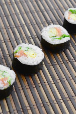 Suşi yalan bir bambu hasır serwing mindere alır. Geleneksel Asya gıda.