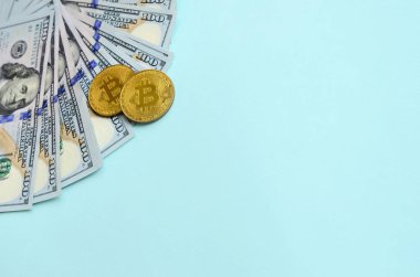 Altın bitcoins ve açık mavi renkli üzerinde yüz dolar faturaları yalan.