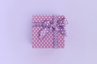 Küçük mor hediye kutusu kurdele ile mor bir arka plan üzerinde yatıyor. Üstten görünüm minimalizm düz yatıyordu.