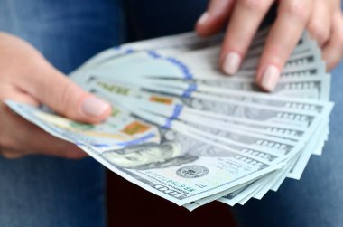 A yelpaze-in yüz dolar Bono tutan bir kız.