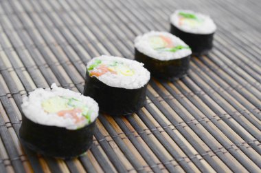 Suşi yalan bir bambu hasır serwing mindere alır. Geleneksel Asya gıda.