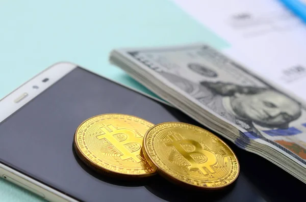 Bitcoins 지폐와 스마트폰 파란색 배경에 있습니다 소득세 신고서 — 스톡 사진