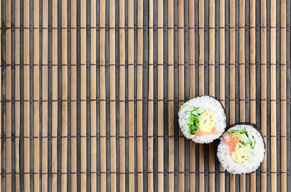 Sushi rolls lies on a bamboo straw serwing mat. Traditional Asian food. Top view. Flat lay minimalism shot with copy space.