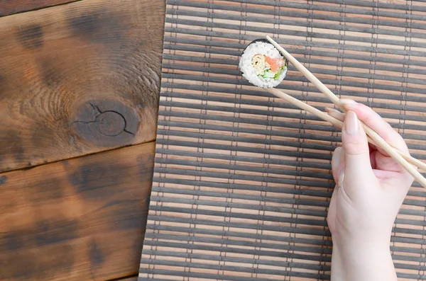Una Mano Con Palillos Sostiene Rollo Sushi Sobre Fondo Paja — Foto de Stock