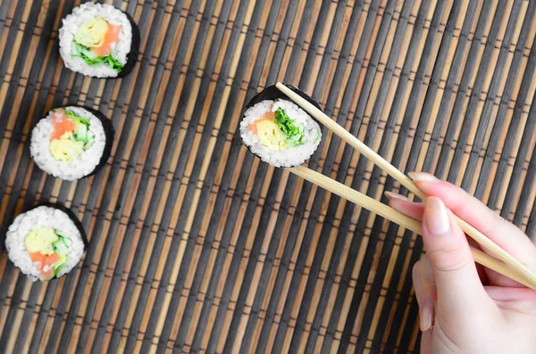 Una Mano Con Bacchette Tiene Rotolo Sushi Uno Sfondo Paglia — Foto Stock