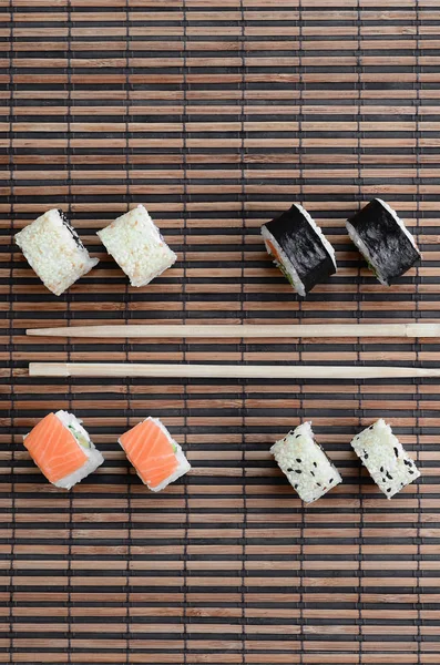 寿司卷和木筷躺在竹稻草 Serwing 传统的亚洲食品 顶部视图 — 图库照片