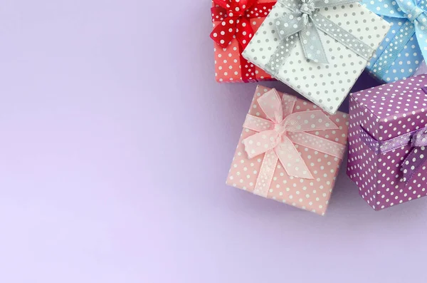 一堆带有丝带的小彩色礼品盒位于紫罗兰色的背景上 简约平躺顶视图 — 图库照片