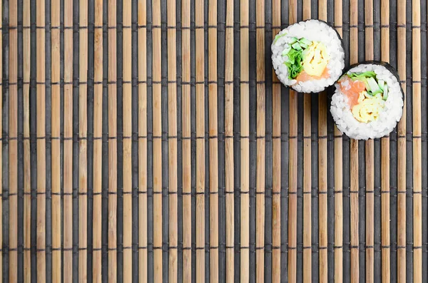 巻き寿司竹わら Serwing マットの上にあります 伝統的なアジア料理 平面図です コピー スペースで撮影フラット レイアウトのミニマリズム — ストック写真
