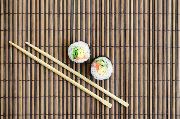 寿司卷和木筷躺在竹稻草 Serwing 传统的亚洲食品 顶部视图 平面平躺极简拍摄与复制空间 — 图库照片