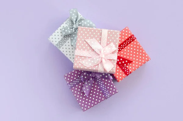 一堆带有丝带的小彩色礼品盒位于紫罗兰色的背景上 简约平躺顶视图 — 图库照片