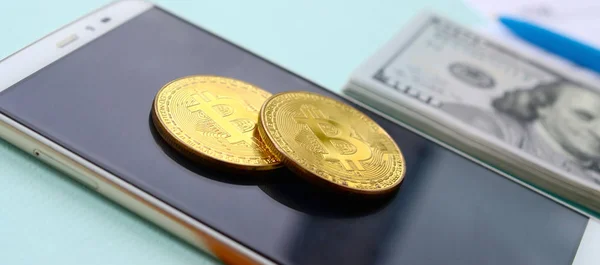 Bitcoins 지폐와 스마트폰 파란색 배경에 있습니다 소득세 신고서 — 스톡 사진