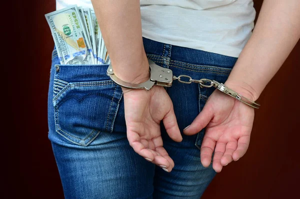 Para büyük miktarda kelepçeli elleriyle tutuklandı bir kızla. Arkadan görünüm.