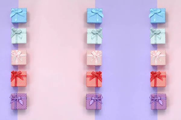 带丝带的不同颜色的小礼品盒位于紫罗兰色和粉红色背景上 — 图库照片