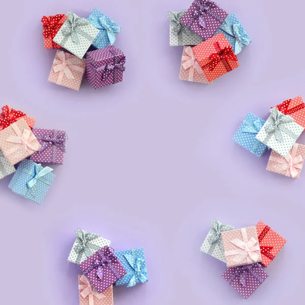 一堆带有丝带的小彩色礼品盒位于紫罗兰色的背景上 简约平躺顶视图模式 — 图库照片