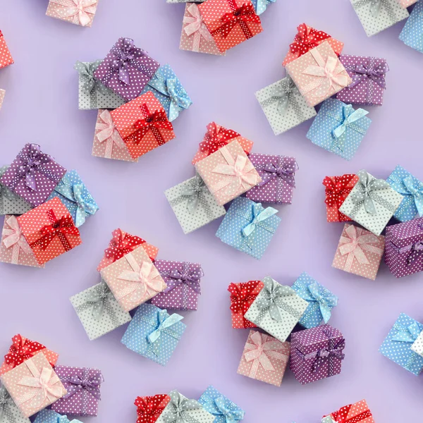 Küçük renkli hediye kutuları şeritler yığınları mor bir arka plan üzerinde yatıyor. Üstten görünüm desen minimalizm düz yatıyordu.