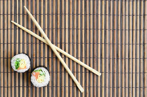 Ρολά Σούσι Και Ξύλινων Chopsticks Βρίσκονται Ένα Χαλί Μπαμπού Άχυρο — Φωτογραφία Αρχείου