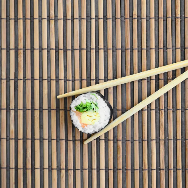 寿司卷和木筷躺在竹稻草 Serwing 传统的亚洲食品 顶部视图 平面平躺极简拍摄与复制空间 — 图库照片
