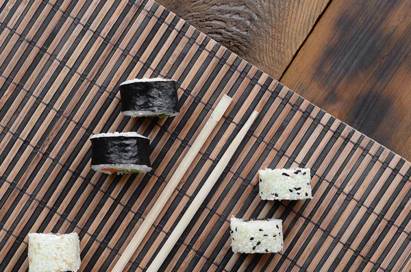 寿司卷和木筷躺在竹稻草 Serwing 传统的亚洲食品 顶部视图 — 图库照片