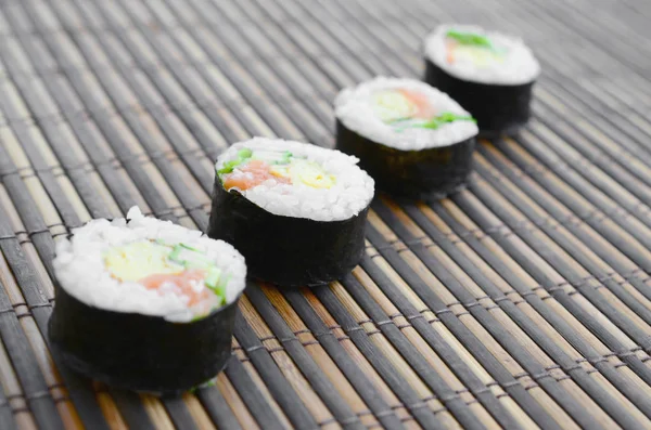 Suşi yalan bir bambu hasır serwing mindere alır. Geleneksel Asya gıda.
