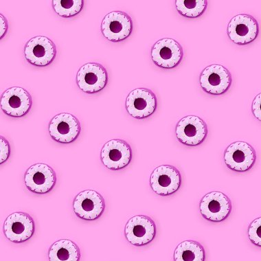 Birçok küçük plastik donuts bir pastel renkli arka plan üzerinde yatıyor. Düz yatıyordu en az desen. Üstten görünüm