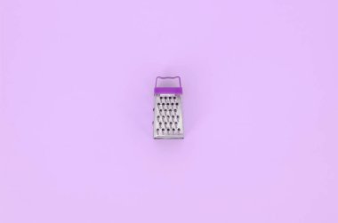 Paslanmaz çelik rende renkli kağıt üzerine pastel yatıyor. Mutfak aksesuarları. Yemek pişirmek için araçlar. Düz yatıyordu üstten görünüm