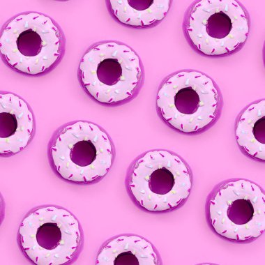 Birçok küçük plastik donuts bir pastel renkli arka plan üzerinde yatıyor. Düz yatıyordu en az desen. Üstten görünüm