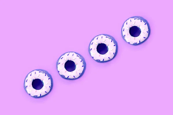 Muitos pequenos donuts de plástico estão em um fundo colorido pastel. Plano leigos padrão mínimo. Vista superior — Fotografia de Stock