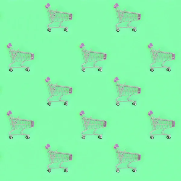 Shopping addiction, shopping lover or shopaholic concept. Many small empty shopping carts perform a pattern on a pastel colored paper background. Flat lay composition, top view — Stock Photo, Image