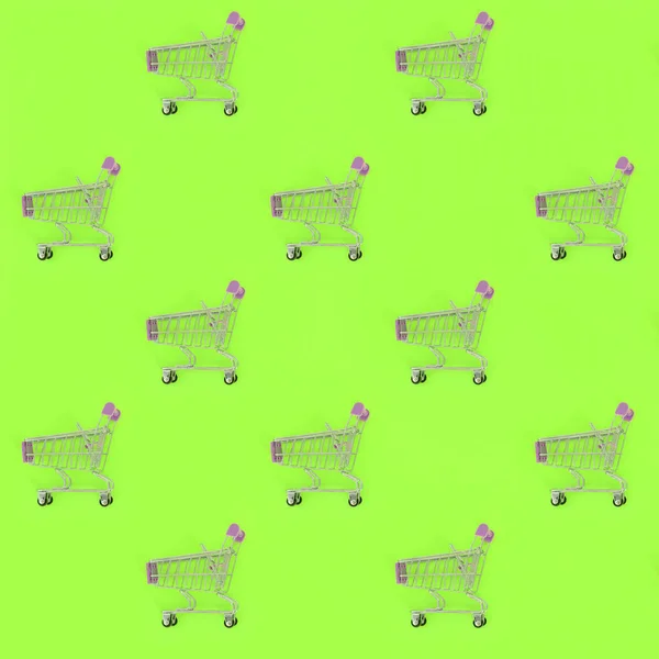 Vício em compras, amante de compras ou conceito shopaholic. Muitos pequenos carrinhos de compras vazios executam um padrão em um fundo de papel colorido pastel. Composição de leigos planos, vista superior — Fotografia de Stock