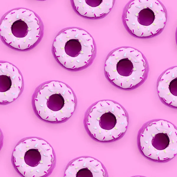 Muchos pequeños donuts de plástico se encuentra en un fondo de colores pastel. Piso establecer un patrón mínimo. Vista superior — Foto de Stock