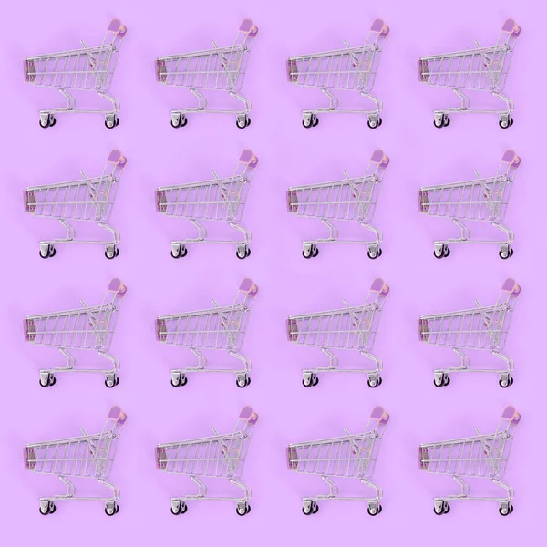 Shopping addiction, shopping lover or shopaholic concept. Many small empty shopping carts perform a pattern on a pastel colored paper background. Flat lay composition, top view — Stock Photo, Image