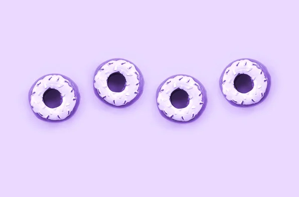 Vele kleine kunststof donuts ligt op een pastel kleurrijke achtergrond. Plat lag minimale patroon. Bovenaanzicht — Stockfoto