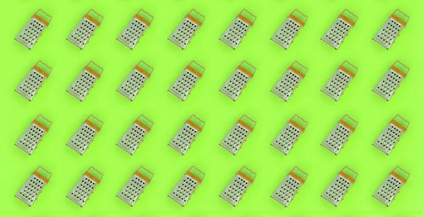 Small stainless steel graters lies on a pastel colored paper. Kitchen accessories. Tools for cooking. Flat lay top view — Stock Photo, Image