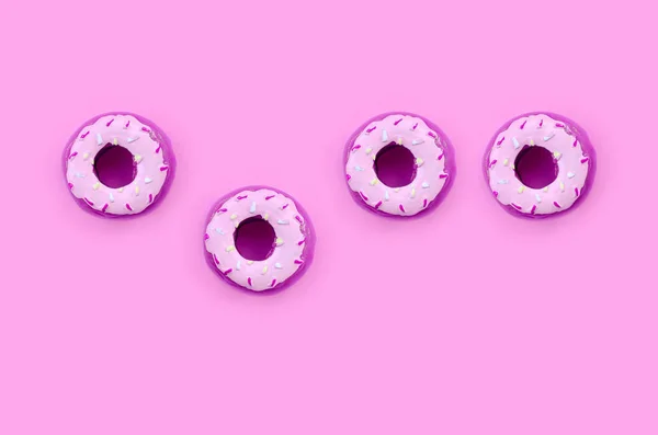 Muchos pequeños donuts de plástico se encuentra en un fondo de colores pastel. Piso establecer un patrón mínimo. Vista superior —  Fotos de Stock