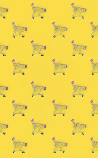 Shopping addiction, shopping lover or shopaholic concept. Many small empty shopping carts perform a pattern on a pastel colored paper background. Flat lay composition, top view — Stock Photo, Image