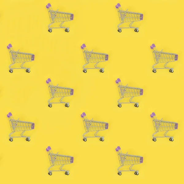 Shopping addiction, shopping lover or shopaholic concept. Many small empty shopping carts perform a pattern on a pastel colored paper background. Flat lay composition, top view — Stock Photo, Image