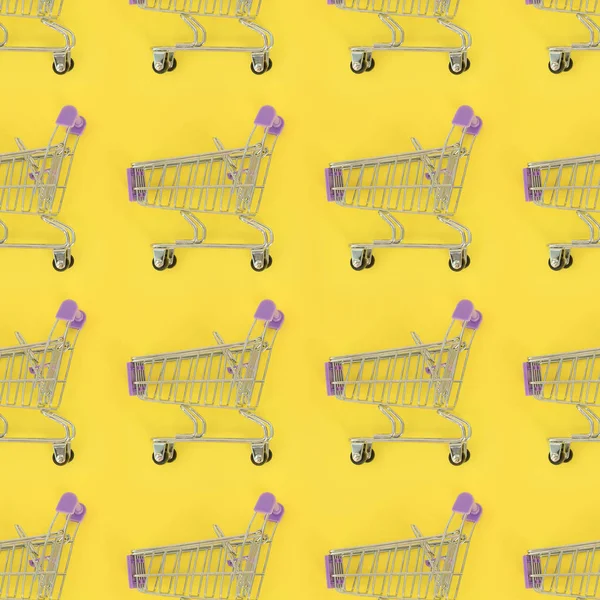 Shopping addiction, shopping lover or shopaholic concept. Many small empty shopping carts perform a pattern on a pastel colored paper background. Flat lay composition, top view — Stock Photo, Image