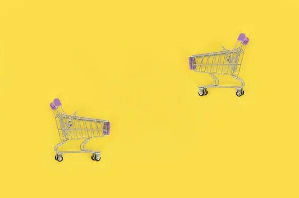 Adicción a las compras, amante de las compras o concepto adicto a las compras. Pequeño carrito de compras vacío se encuentra sobre un fondo de papel de color pastel. Redacción plana composición mínima, vista superior —  Fotos de Stock