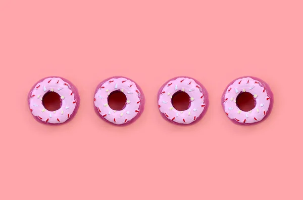 Muchos pequeños donuts de plástico se encuentra en un fondo de colores pastel. Piso establecer un patrón mínimo. Vista superior — Foto de Stock