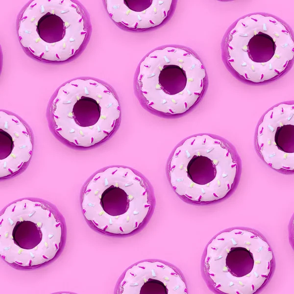 Muchos pequeños donuts de plástico se encuentra en un fondo de colores pastel. Piso establecer un patrón mínimo. Vista superior — Foto de Stock