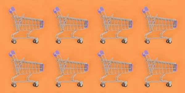 Adicción a las compras, amante de las compras o concepto adicto a las compras. Muchos pequeños carros de compras vacíos realizan un patrón sobre un fondo de papel de color pastel. Composición plana, vista superior —  Fotos de Stock