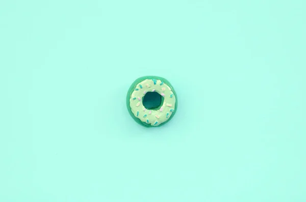 単一の小さなプラスチック製のドーナツは、パステル調のカラフルな背景にあります。フラット レイアウトの最小構成。トップ ビュー — ストック写真
