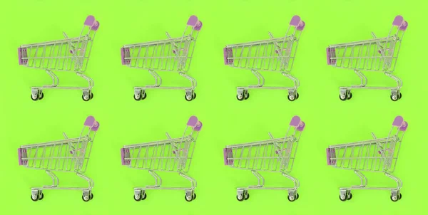 Shopping addiction, shopping lover or shopaholic concept. Many small empty shopping carts perform a pattern on a pastel colored paper background. Flat lay composition, top view — Stock Photo, Image